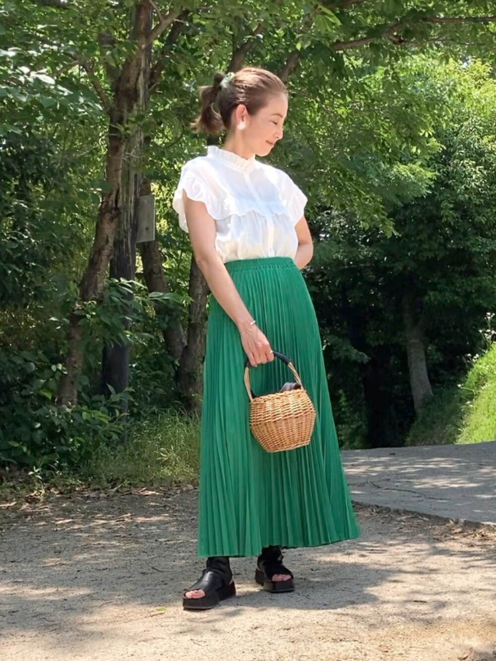 グリーン系のスカート、ホワイト系のシャツ/ブラウス、ブラック系のブーツを着用したレディースの夏コーディネートの1枚目の写真