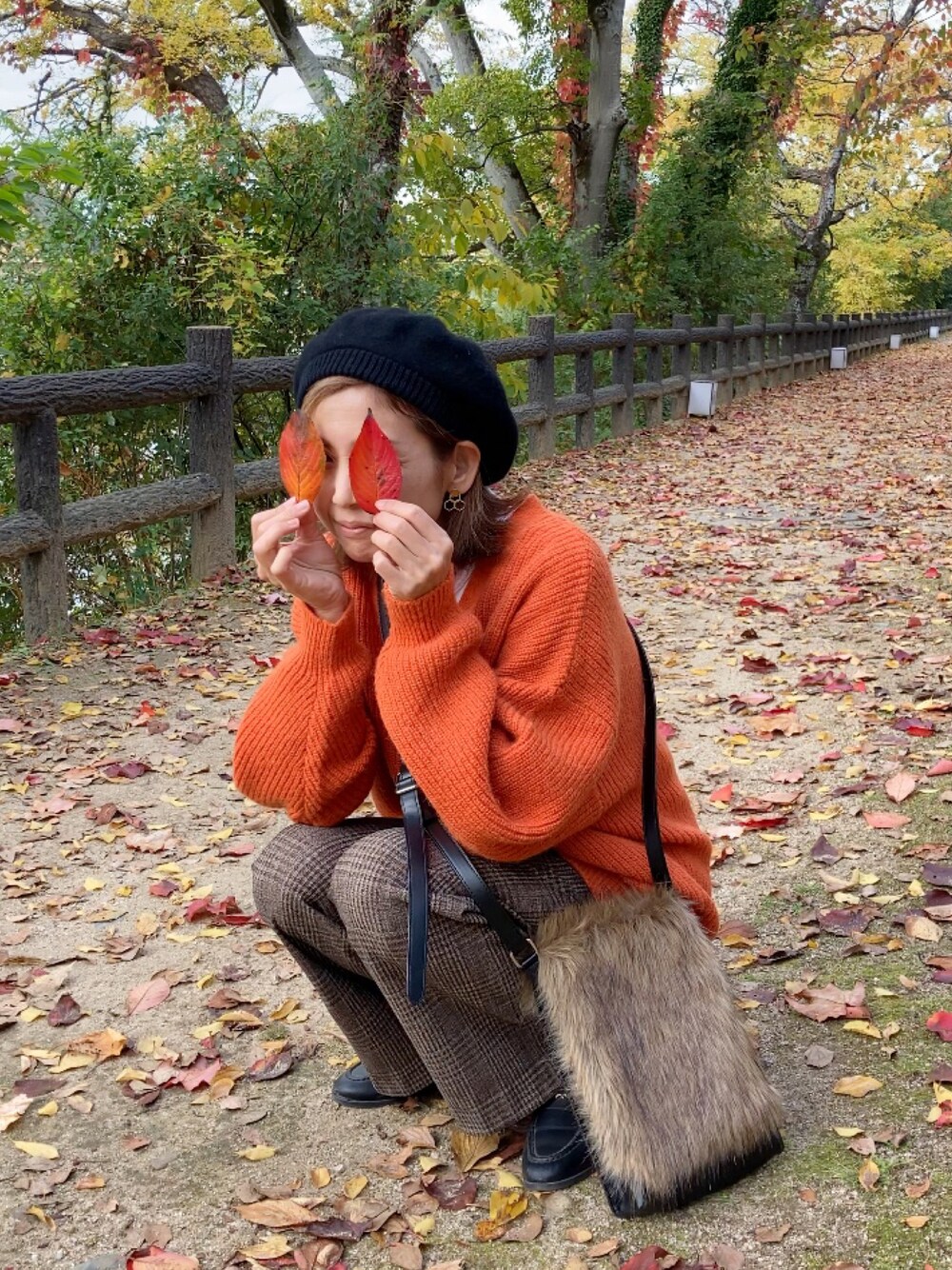 ブラウン系のパンツ、オレンジ系のカーディガン/ボレロ、ブラウン系のショルダーバッグを着用したレディースの秋コーディネートの1枚目の写真