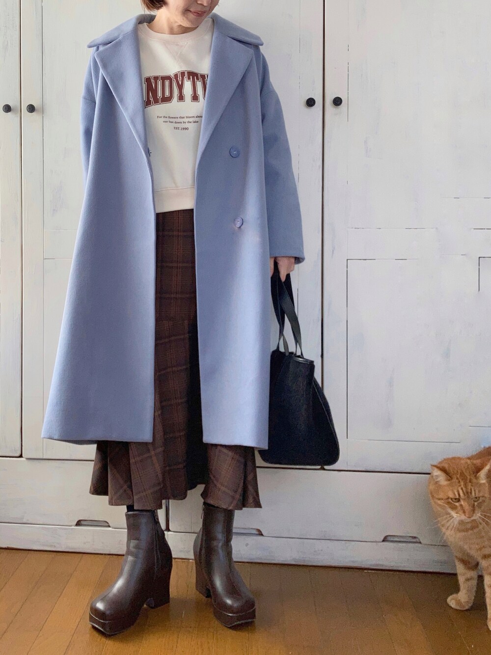 ブルー系のチェスターコート、ホワイト系のスウェット、ブラウン系のスカートを着用したレディースの冬コーディネートの1枚目の写真