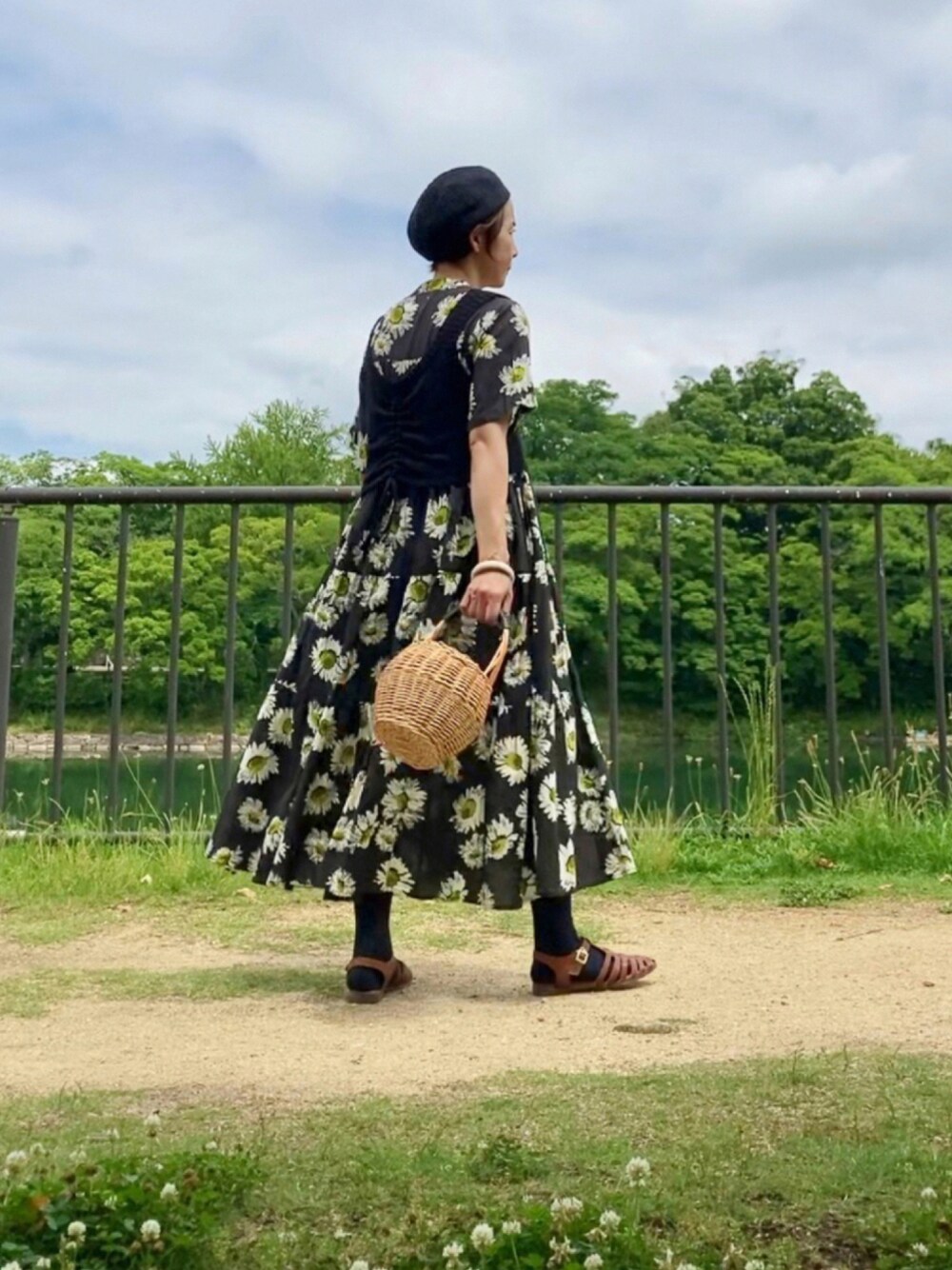 ブラック系のベスト、ブラック系のワンピース、ベージュ系のかごバッグを着用したレディースの夏コーディネートの1枚目の写真