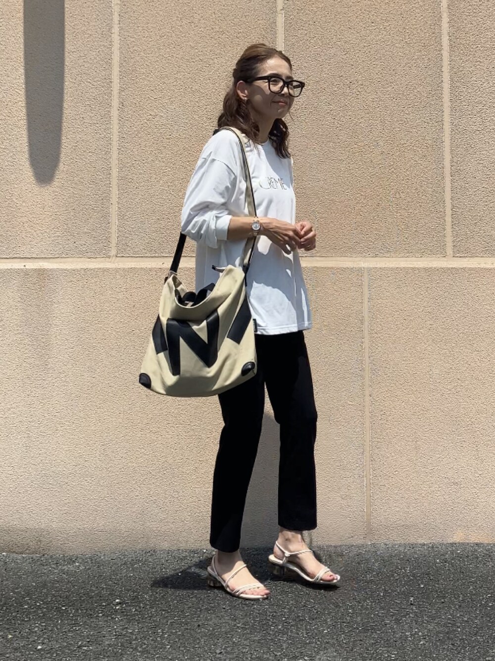 ホワイト系のTシャツ/カットソー、ブラック系のパンツ、ベージュ系のトートバッグを着用したレディースの夏コーディネートの1枚目の写真