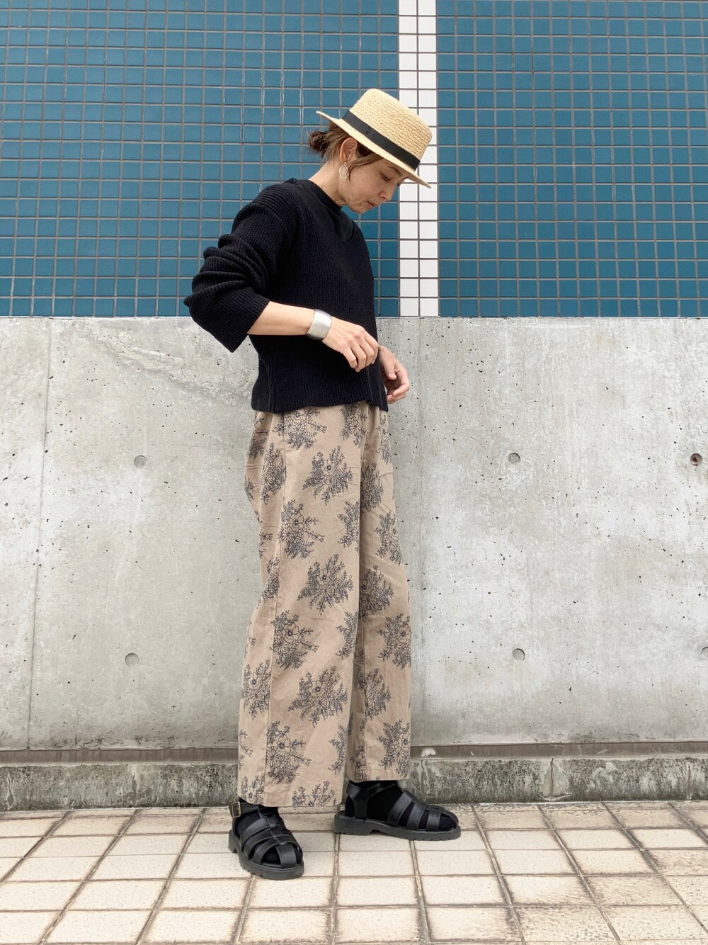 ベージュ系のパンツ、ブラック系のニット/セーター、ブラック系のサンダルを着用したレディースの春コーディネートの1枚目の写真