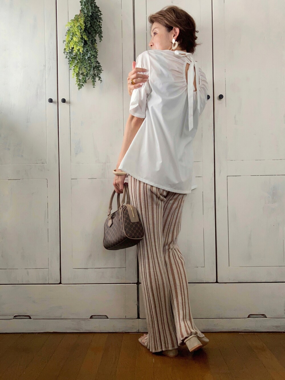 ホワイト系のシャツ/ブラウス、ブラウン系のその他パンツ、ブラウン系のボストンバッグを着用したレディースの夏コーディネートの1枚目の写真