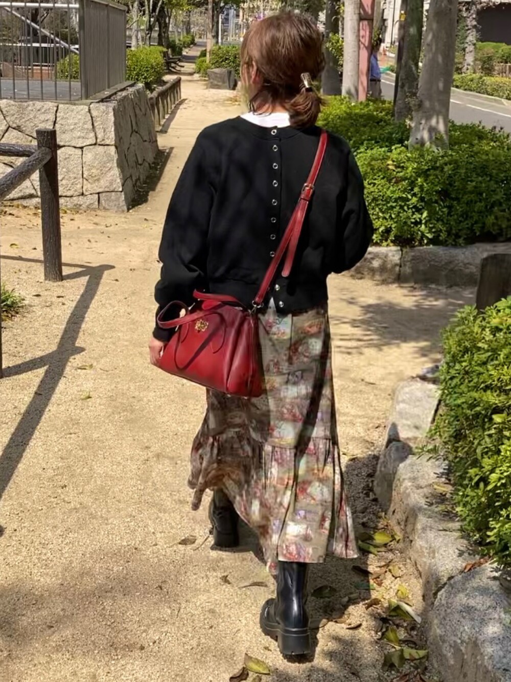 ブラック系のスウェット、レッド系のハンドバッグ、グリーン系のスカートを着用したレディースの春コーディネートの1枚目の写真