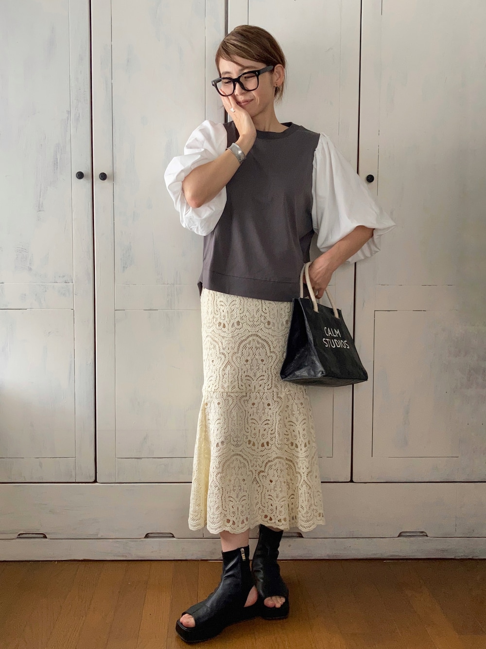 ブラック系のその他トップス、ホワイト系のスカート、ブラック系のブーツを着用したレディースの春コーディネートの1枚目の写真