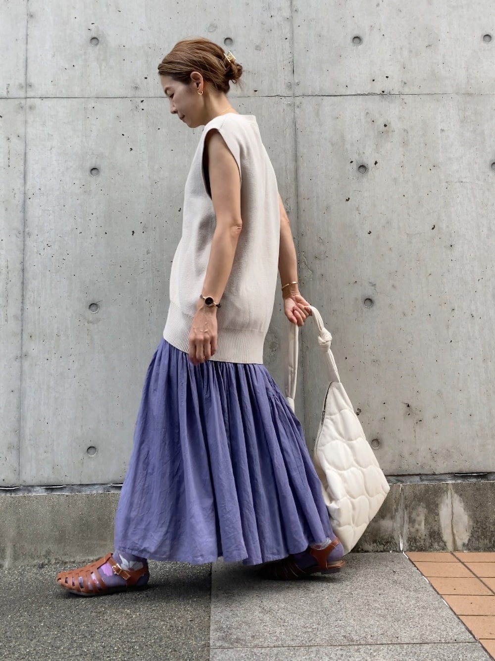 ベージュ系のベスト、グレー系のスカート、ホワイト系のショルダーバッグを着用したレディースの夏コーディネートの1枚目の写真