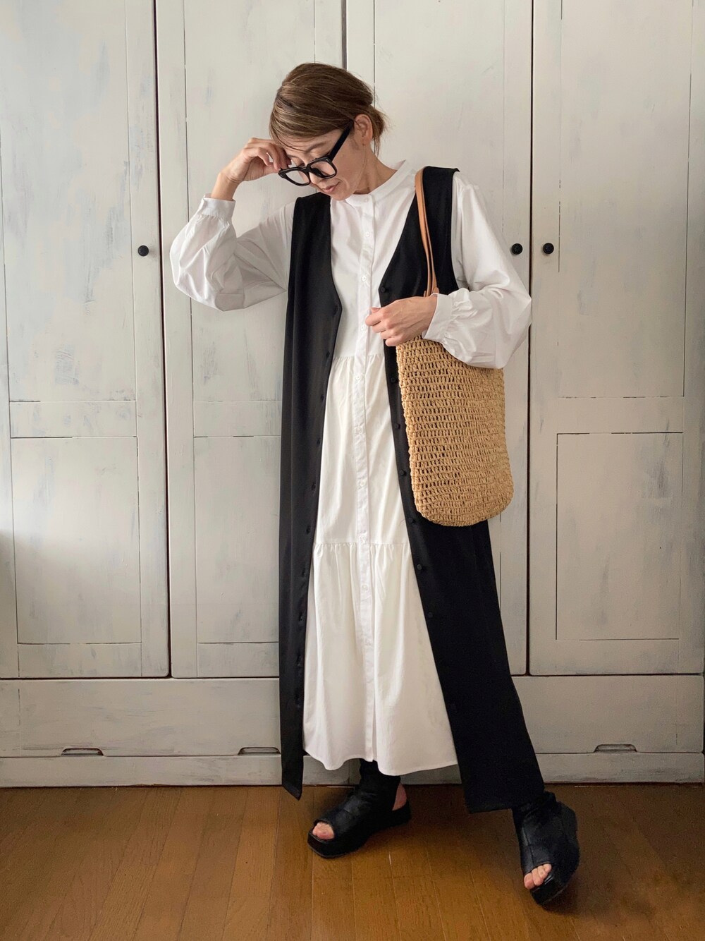 ブラック系のジャンパースカート、ホワイト系のワンピース/ドレス、ベージュ系のバッグを着用したレディースの春コーディネートの1枚目の写真