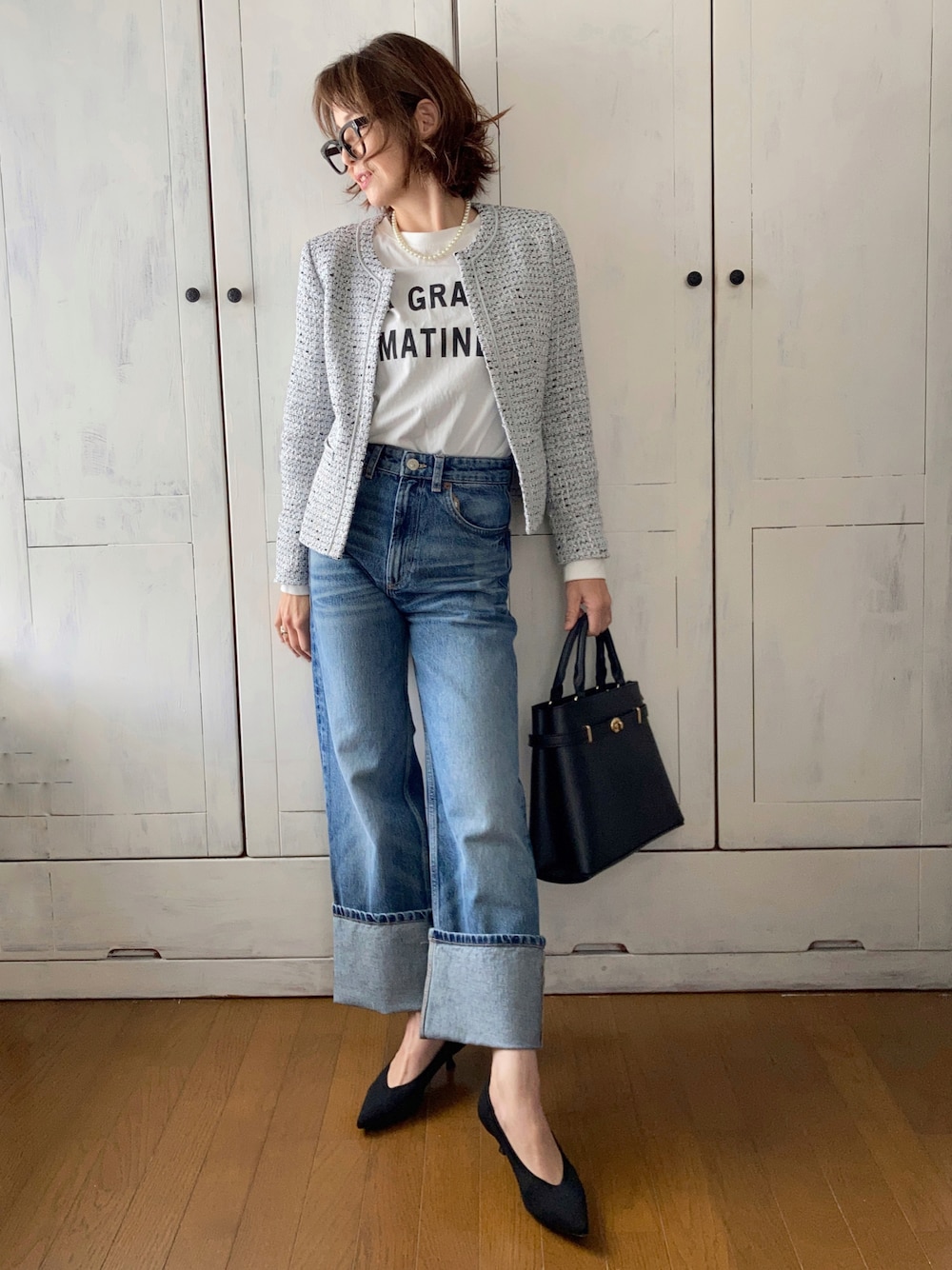 ブルー系のスーツセット、ブルー系のデニムパンツ、ブラック系のハンドバッグを着用したレディースの冬コーディネートの1枚目の写真