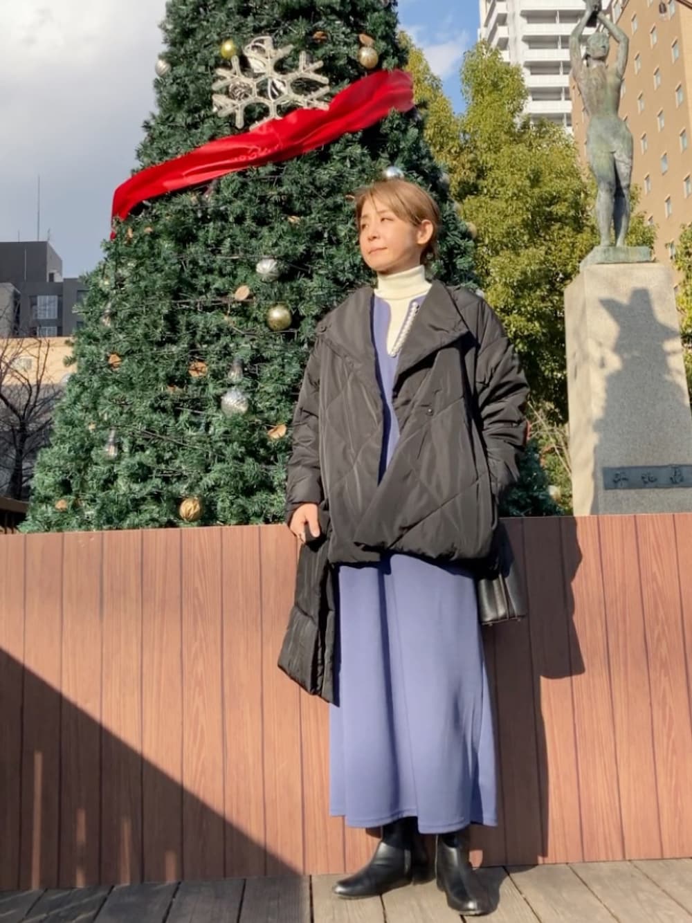 ブラック系のダウンジャケット/コート、ブルー系のワンピース、ブラック系のハンドバッグを着用したレディースの冬コーディネートの1枚目の写真