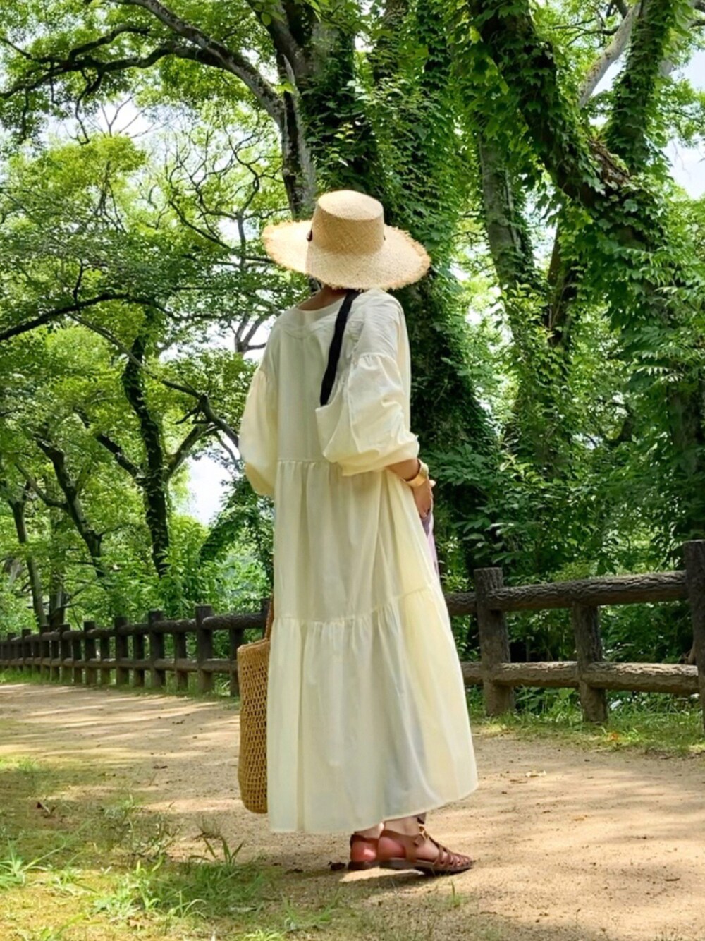 ホワイト系のワンピース、ブラウン系のサンダル、ベージュ系のバッグを着用したレディースの夏コーディネートの1枚目の写真