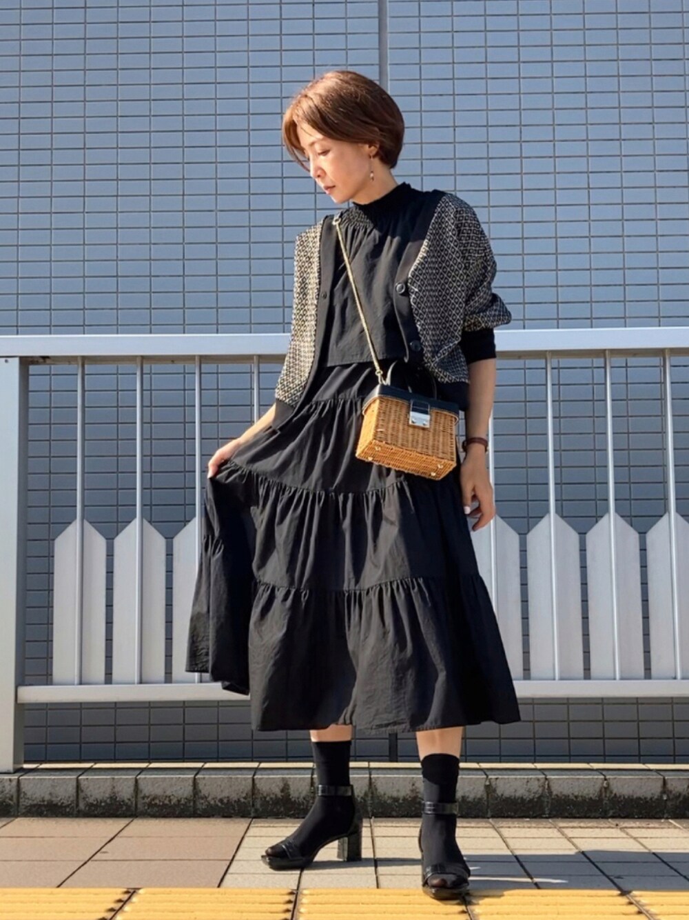 ブラック系のワンピース、ブラック系のTシャツ/カットソー、ブラウン系のかごバッグを着用したレディースの夏コーディネートの1枚目の写真