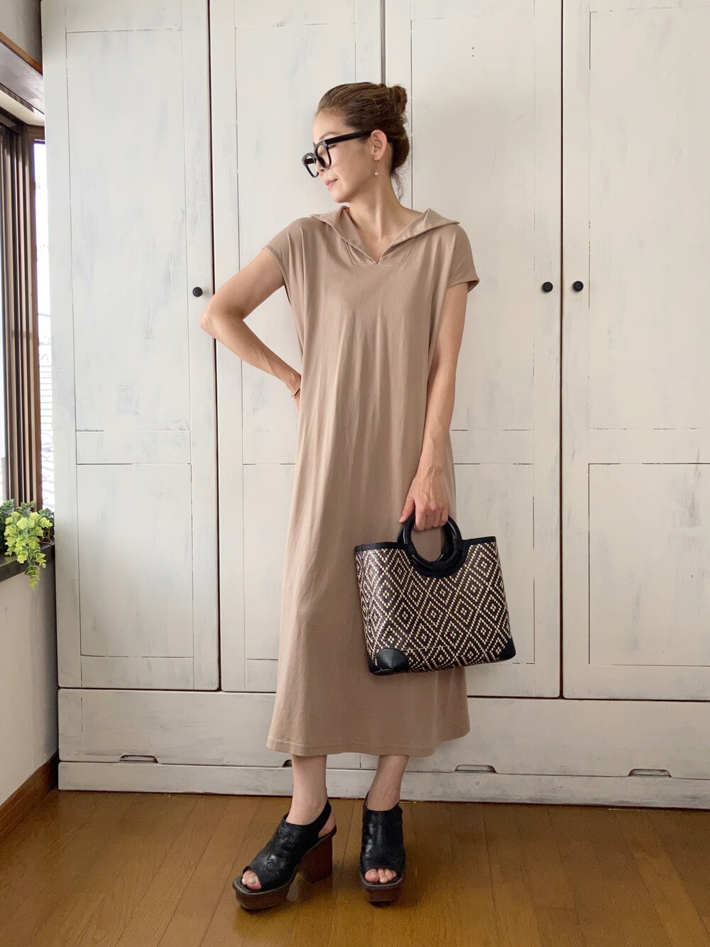 ベージュ系のワンピース、ブラック系のかごバッグ、ブラック系のサンダルを着用したレディースの夏コーディネートの1枚目の写真