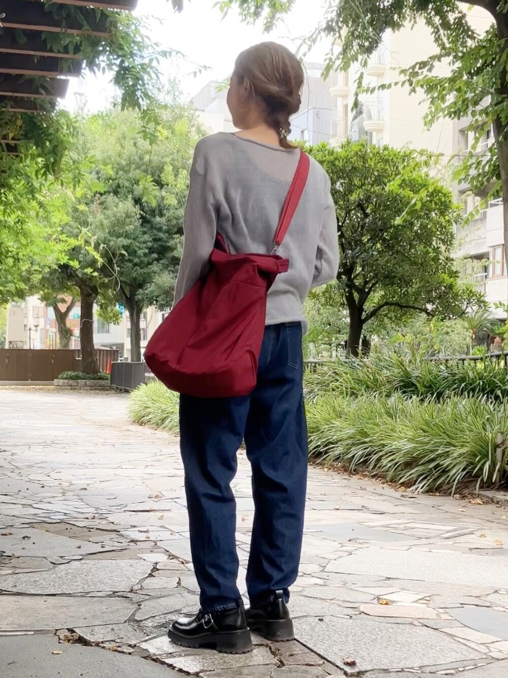 レッド系のボストンバッグ、グレー系のその他トップス、ブルー系のデニムパンツを着用したレディースの秋コーディネートの1枚目の写真