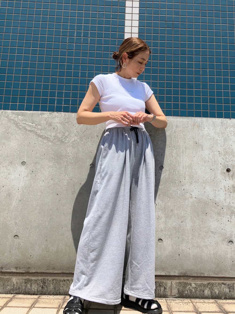 ホワイト系のTシャツ/カットソー、グレー系のスウェットパンツ、ブラック系のサンダルを着用したレディースの春コーディネートの1枚目の写真