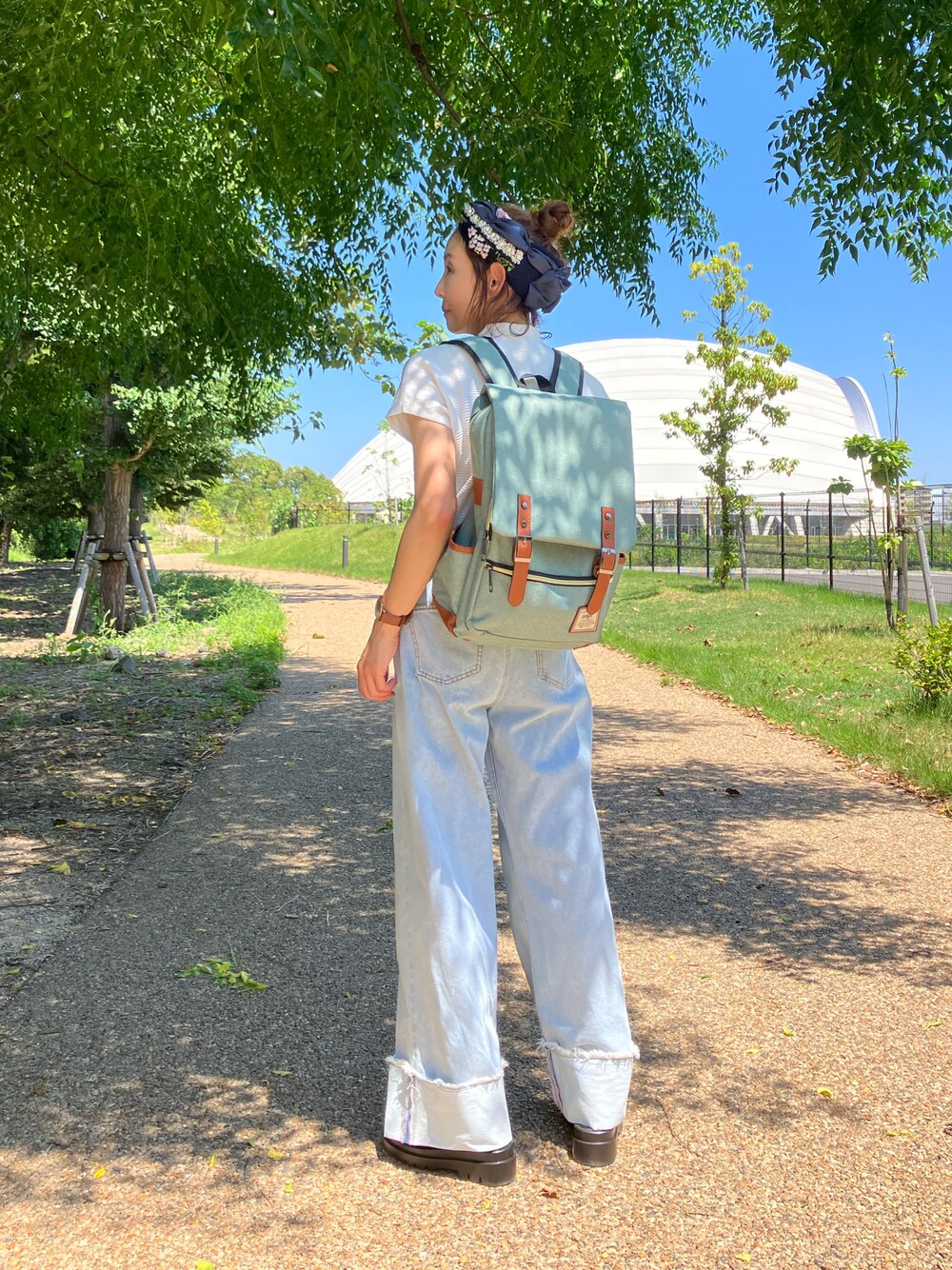 グリーン系のバックパック/リュック、ホワイト系のTシャツ/カットソー、ブルー系のデニムパンツを着用したレディースの夏コーディネートの1枚目の写真