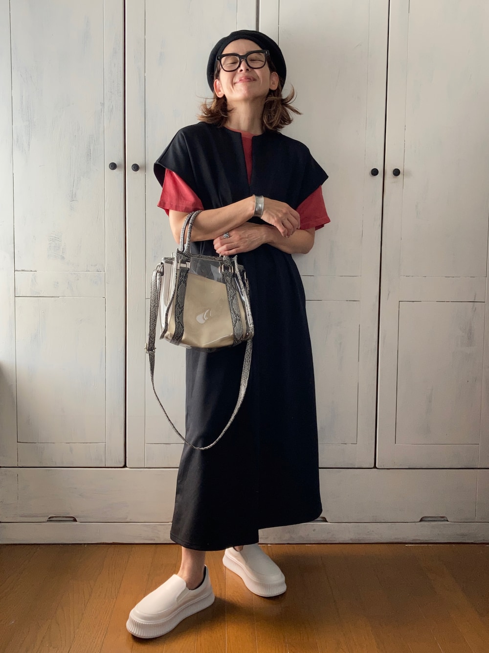 ブラック系のワンピース、レッド系のトップス、ホワイト系のスリッポンを着用したレディースの夏コーディネートの1枚目の写真