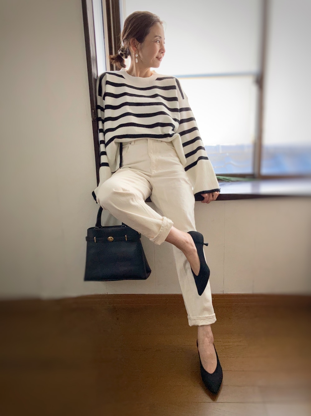 ブラック系のパンプス、ホワイト系のニット/セーター、ブラック系のハンドバッグを着用したレディースの冬コーディネートの1枚目の写真