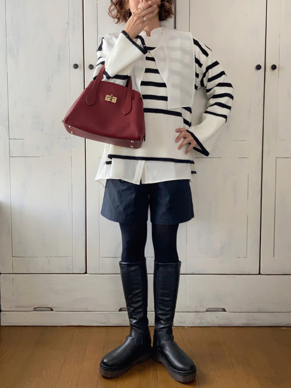 ホワイト系のシャツ/ブラウス、ホワイト系のニット/セーター、ブラック系のハンドバッグを着用したレディースの冬コーディネートの1枚目の写真