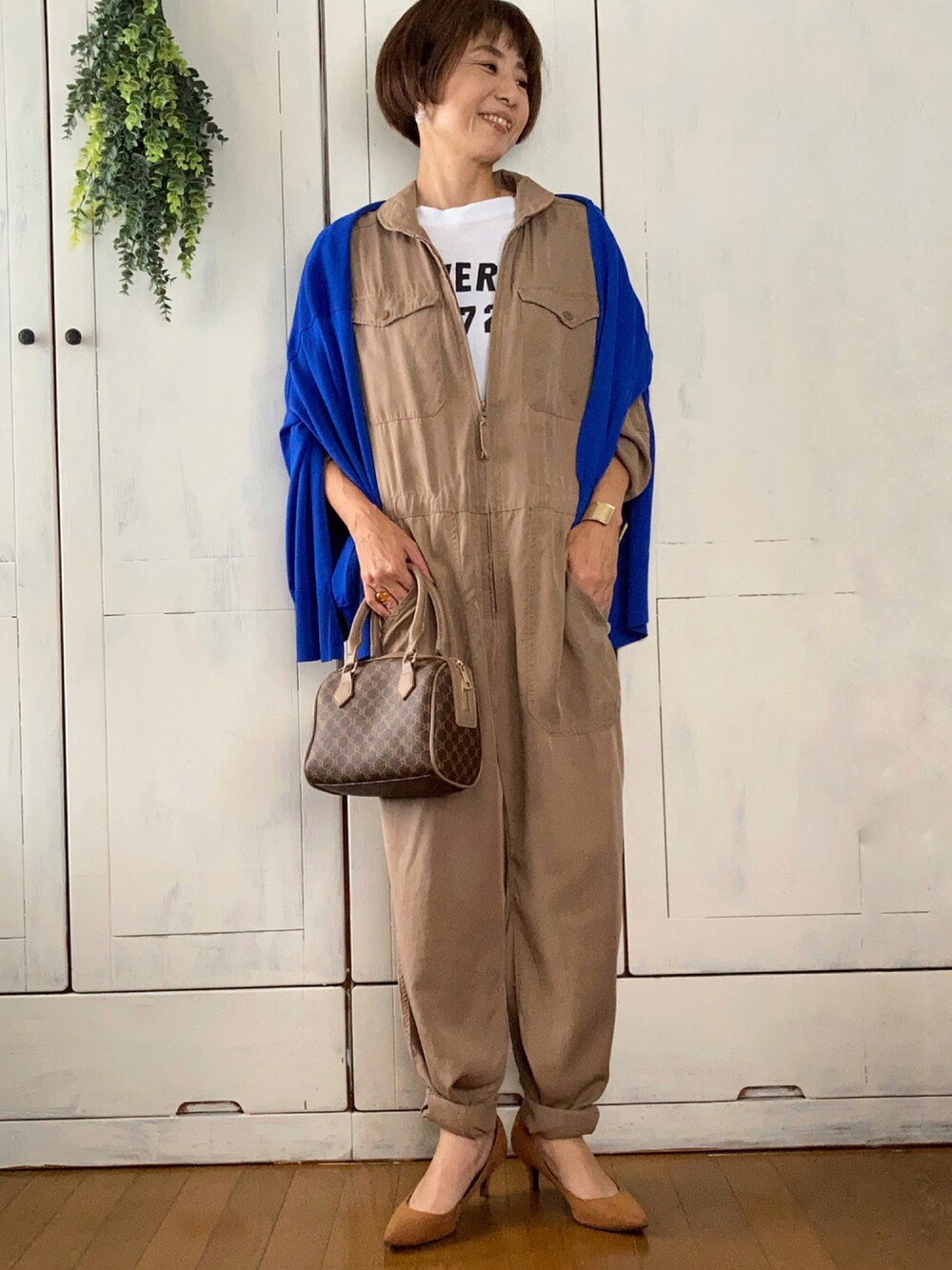 ベージュ系のつなぎ/オールインワン、ブルー系のカーディガン/ボレロ、ホワイト系のTシャツ/カットソーを着用したレディースの秋コーディネートの1枚目の写真