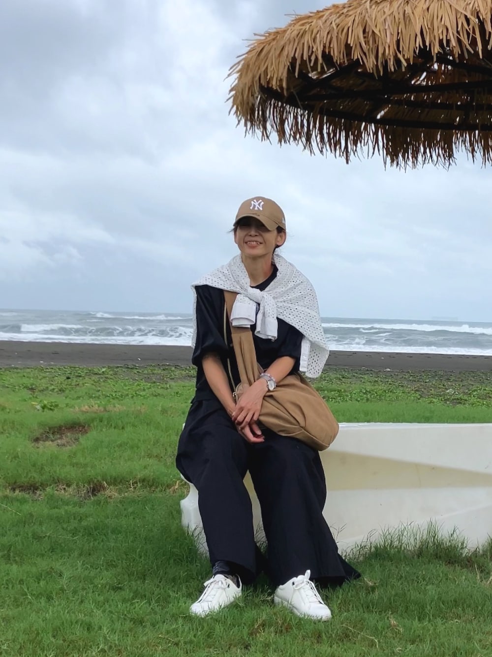 ブラック系のトップス、ベージュ系のショルダーバッグ、ブラック系のパンツを着用したレディースの夏コーディネートの1枚目の写真