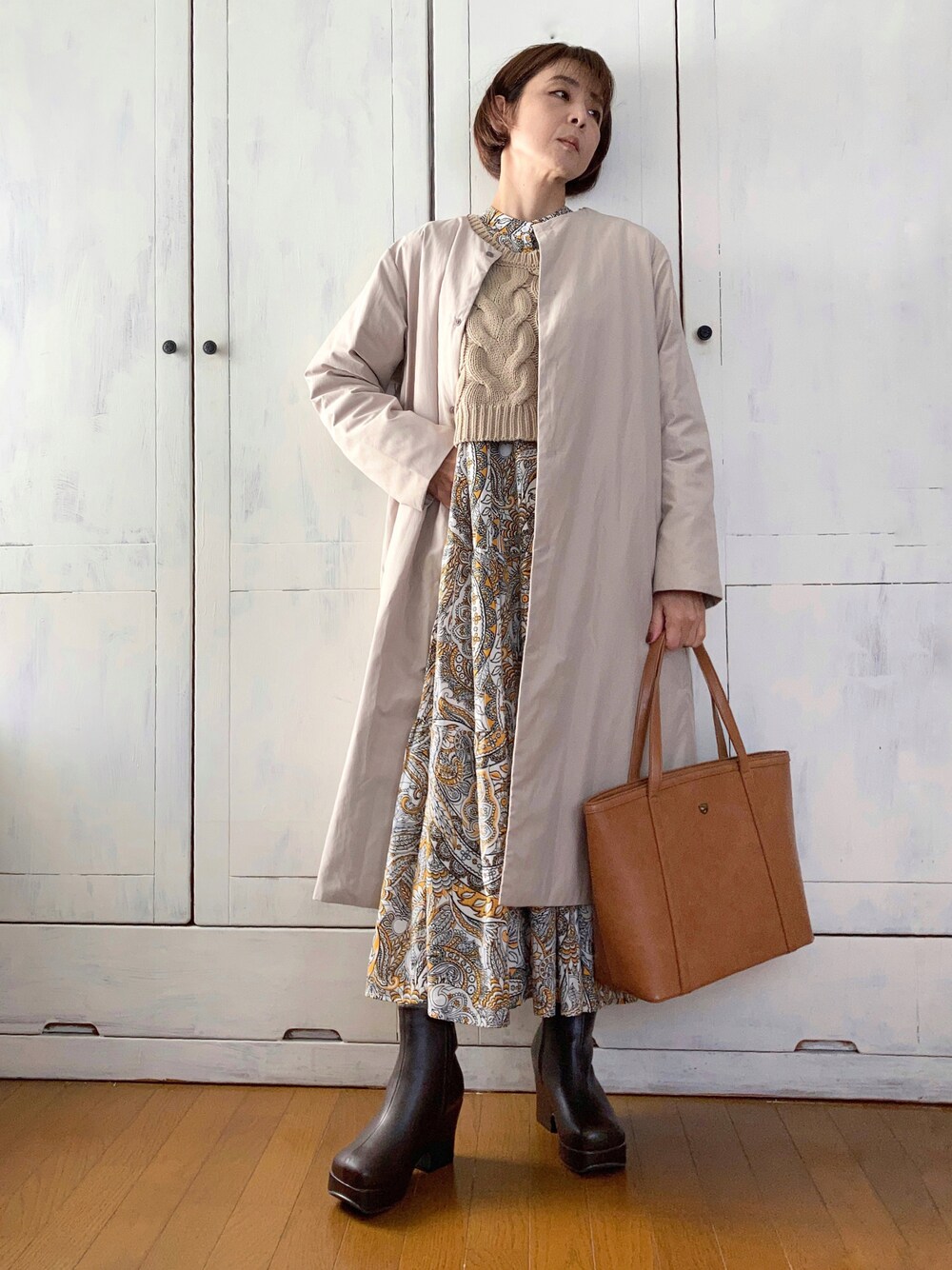 ベージュ系のダウンジャケット/コート、イエロー系のワンピース、ベージュ系のベストを着用したレディースの秋コーディネートの1枚目の写真