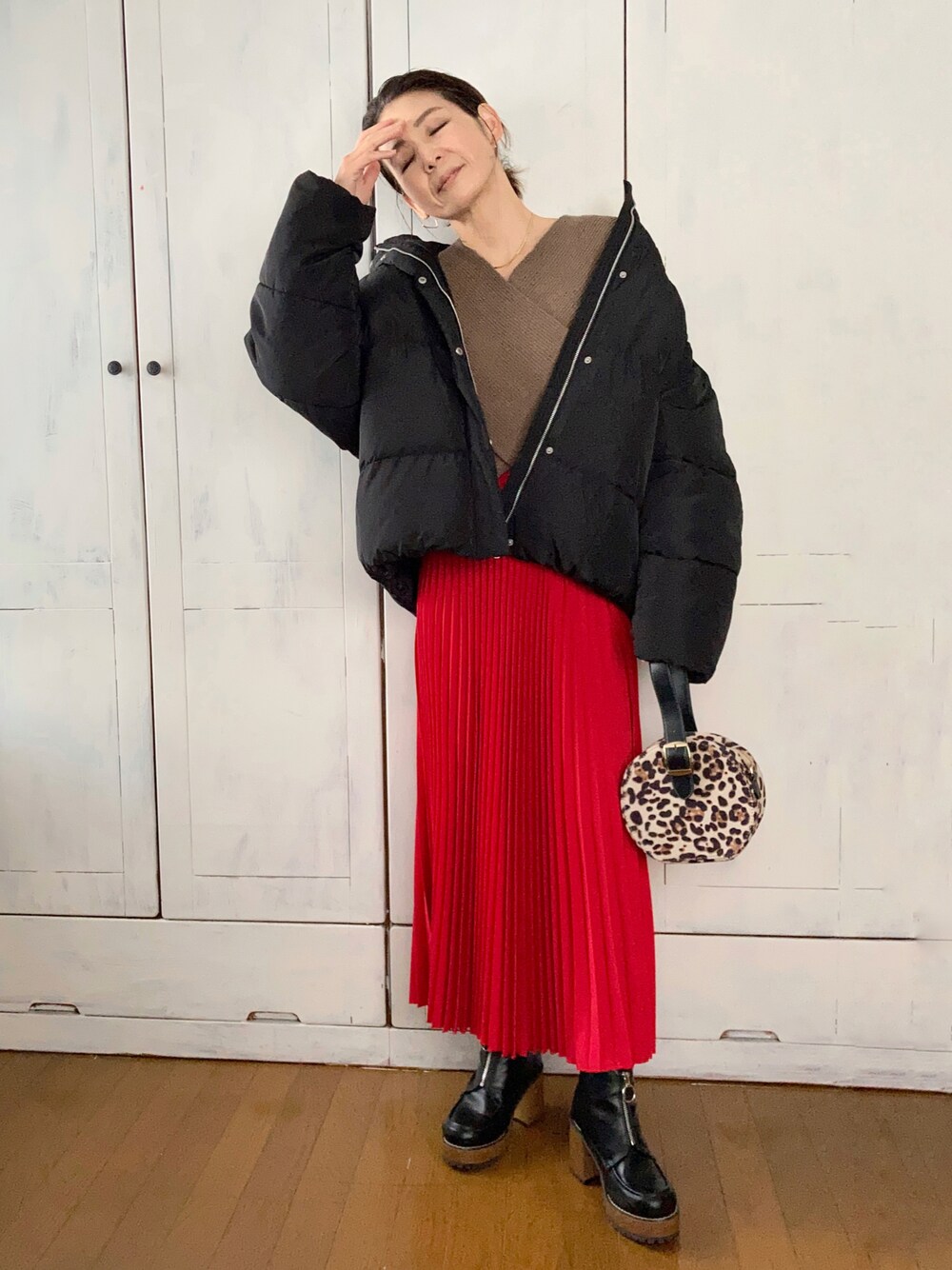 ブラック系のダウンジャケット/コート、ブラウン系のニット/セーター、レッド系のスカートを着用したレディースの冬コーディネートの1枚目の写真