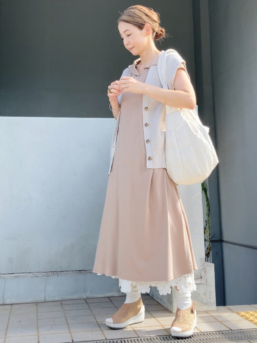 ベージュ系のベスト、ベージュ系のワンピース、ホワイト系のショルダーバッグを着用したレディースの夏コーディネートの1枚目の写真