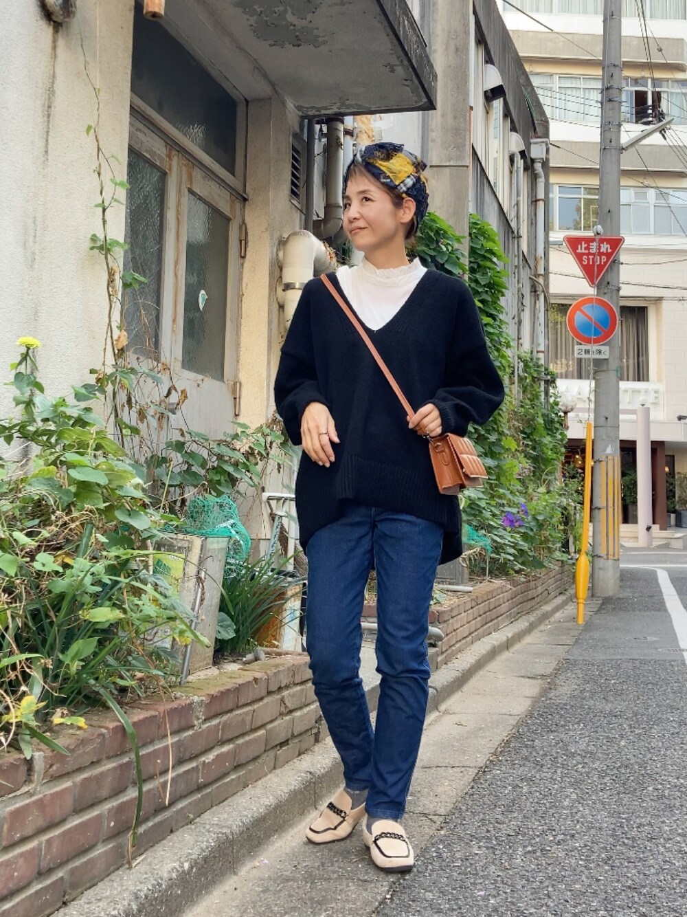 ブラック系のニット/セーター、ブルー系のデニムパンツ、ベージュ系のシューズを着用したレディースの秋コーディネートの1枚目の写真