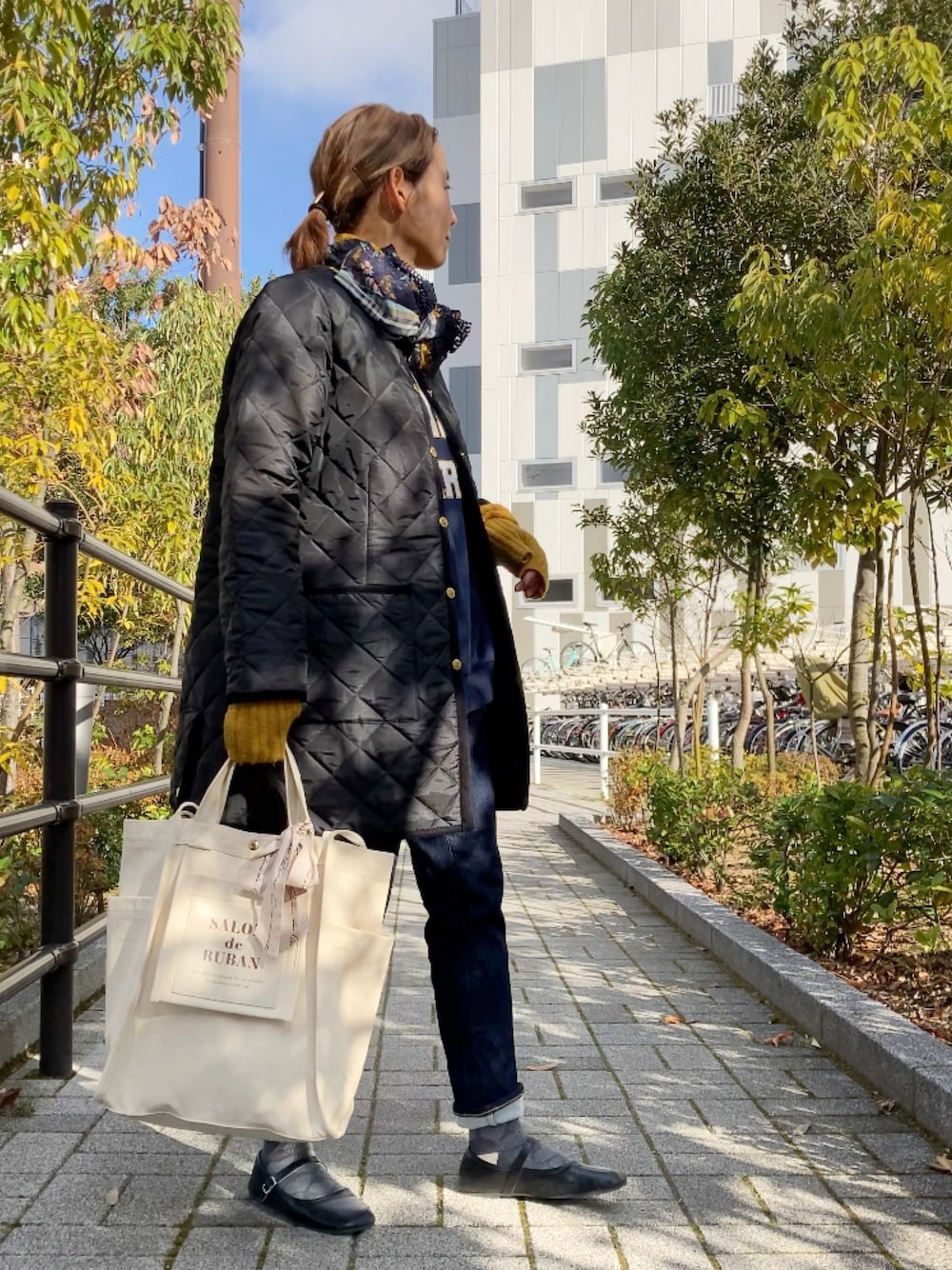 ブラック系のその他アウター、ホワイト系のトートバッグ、ブルー系のデニムパンツを着用したレディースの冬コーディネートの1枚目の写真