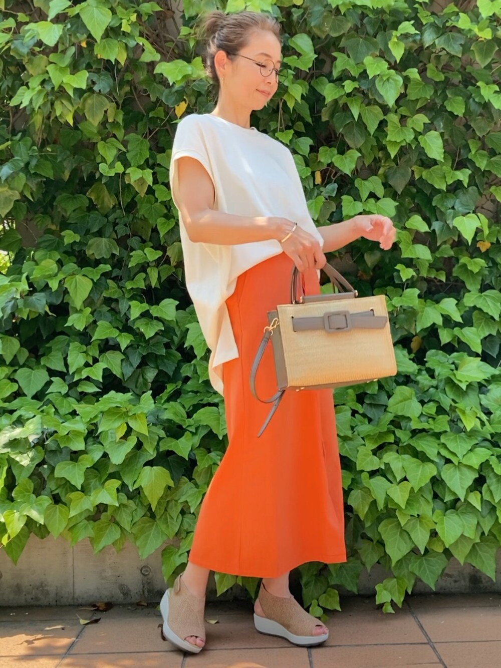ホワイト系のTシャツ/カットソー、オレンジ系のスカート、グレー系のハンドバッグを着用したレディースの春コーディネートの1枚目の写真