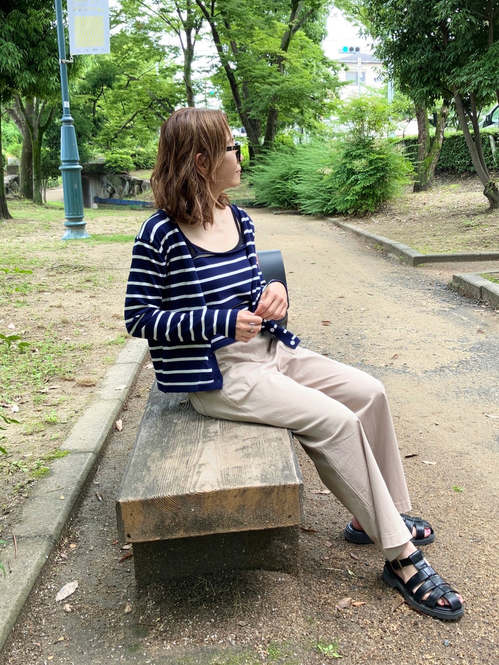 ブルー系のアンサンブル、ベージュ系のパンツ、ブラック系のサンダルを着用したレディースの夏コーディネートの1枚目の写真