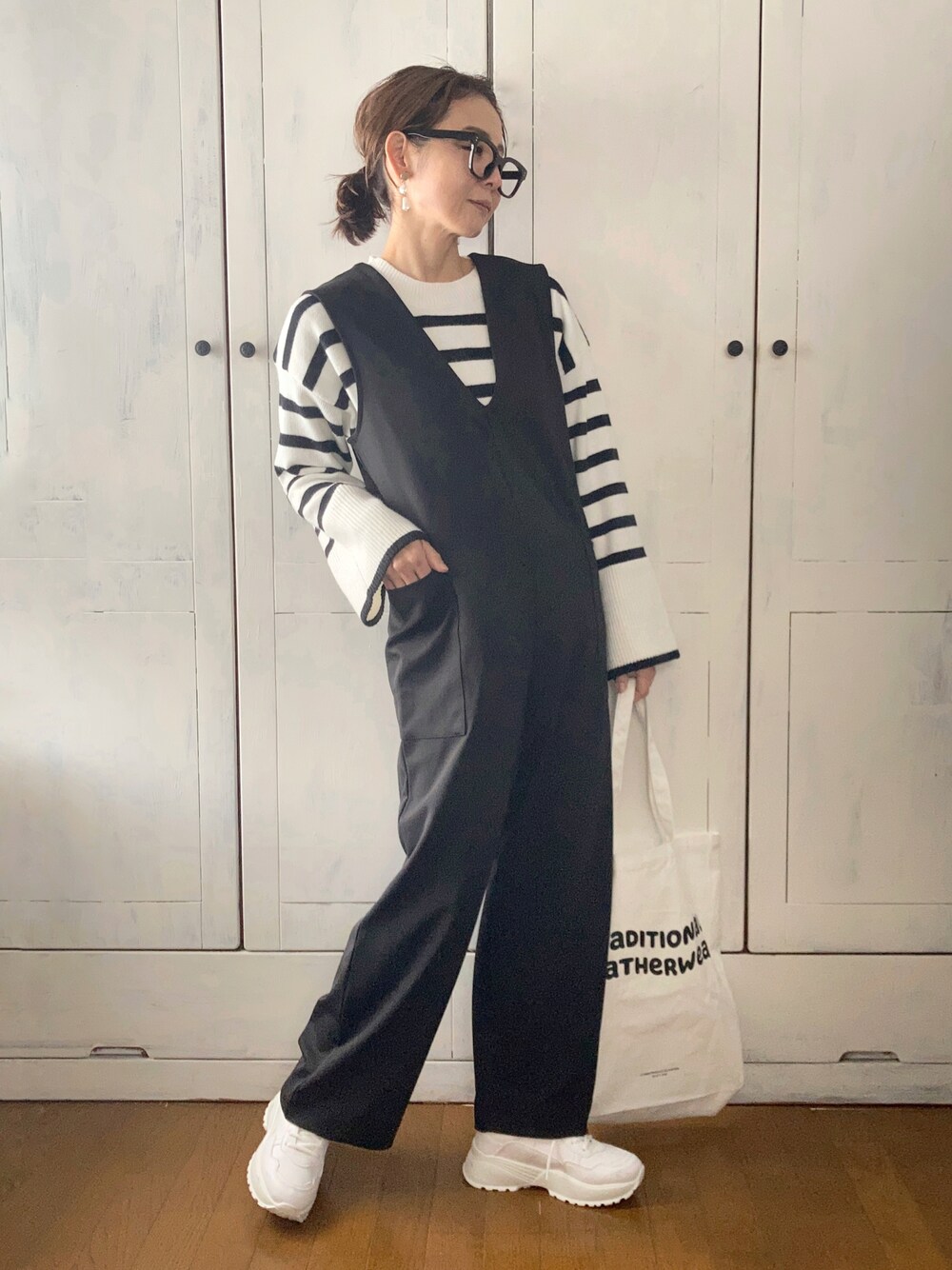 ブラック系のつなぎ/オールインワン、ホワイト系のニット/セーター、ホワイト系のトートバッグを着用したレディースの冬コーディネートの1枚目の写真