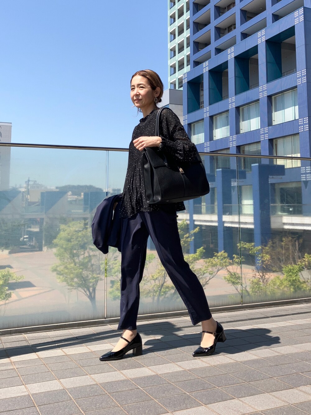 ブルー系のスーツセット、ブラック系のシャツ/ブラウス、ブラック系のビジネスバッグを着用したレディースの春コーディネートの1枚目の写真