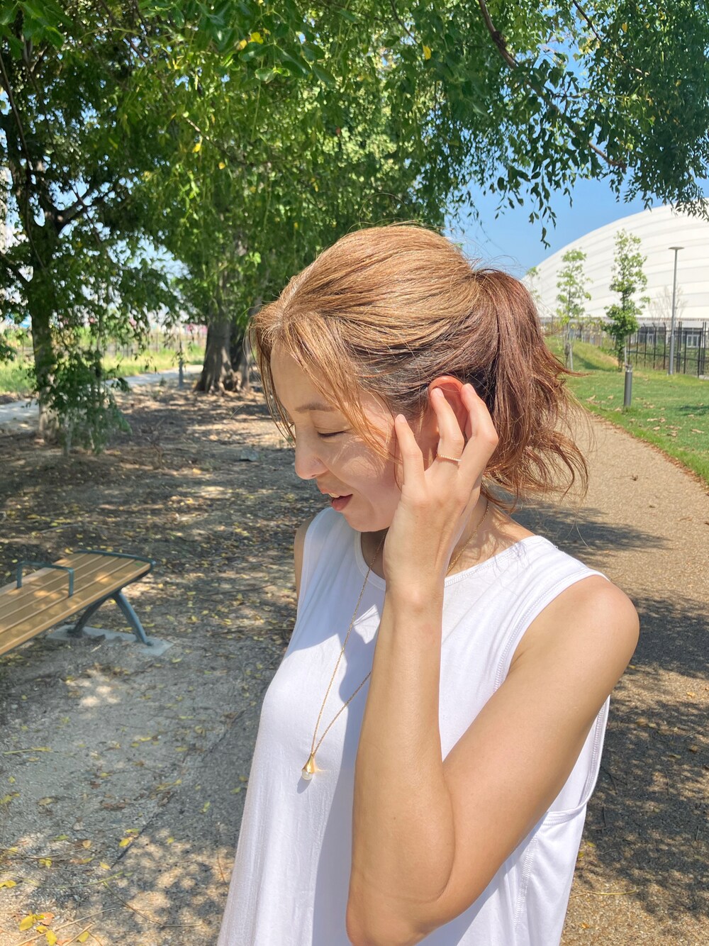 ホワイト系のタンクトップ、ブルー系のデニムパンツ、ブラック系のショルダーバッグを着用したレディースの夏コーディネートの1枚目の写真