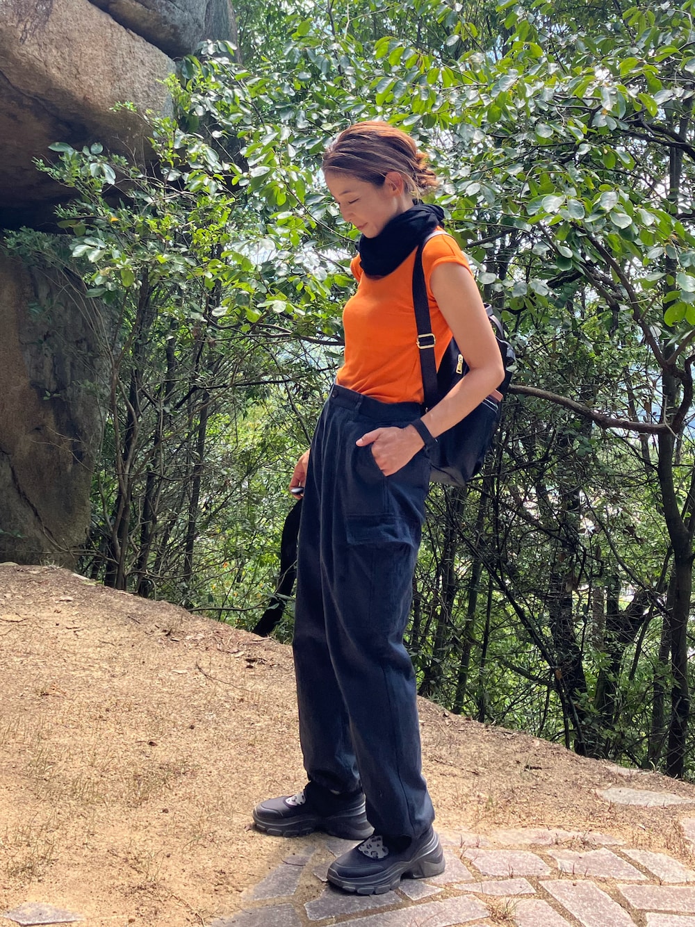 オレンジ系のTシャツ/カットソー、ブラック系のカーディガン/ボレロ、ブラック系のカーゴパンツを着用したレディースの秋コーディネートの1枚目の写真