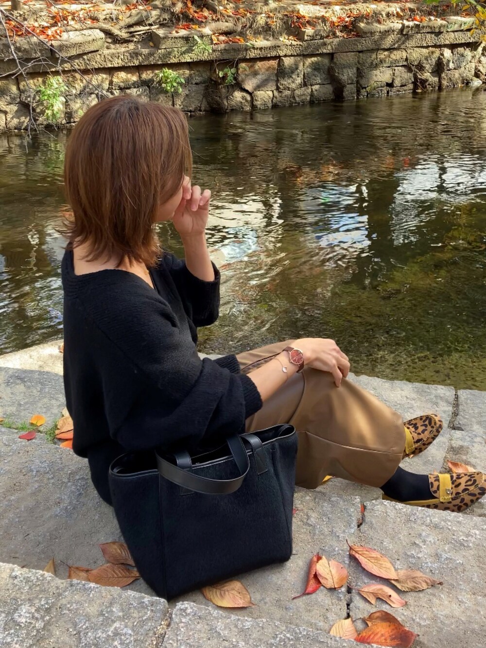 ブラック系のニット/セーター、ブラウン系のスカート、ブラック系のトートバッグを着用したレディースの秋コーディネートの1枚目の写真