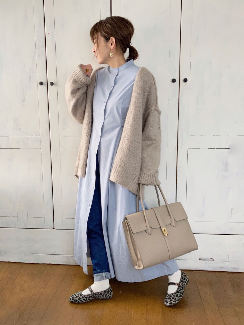 ブルー系のシャツワンピース、ベージュ系のカーディガン/ボレロ、ベージュ系のビジネスバッグを着用したレディースの冬コーディネートの1枚目の写真