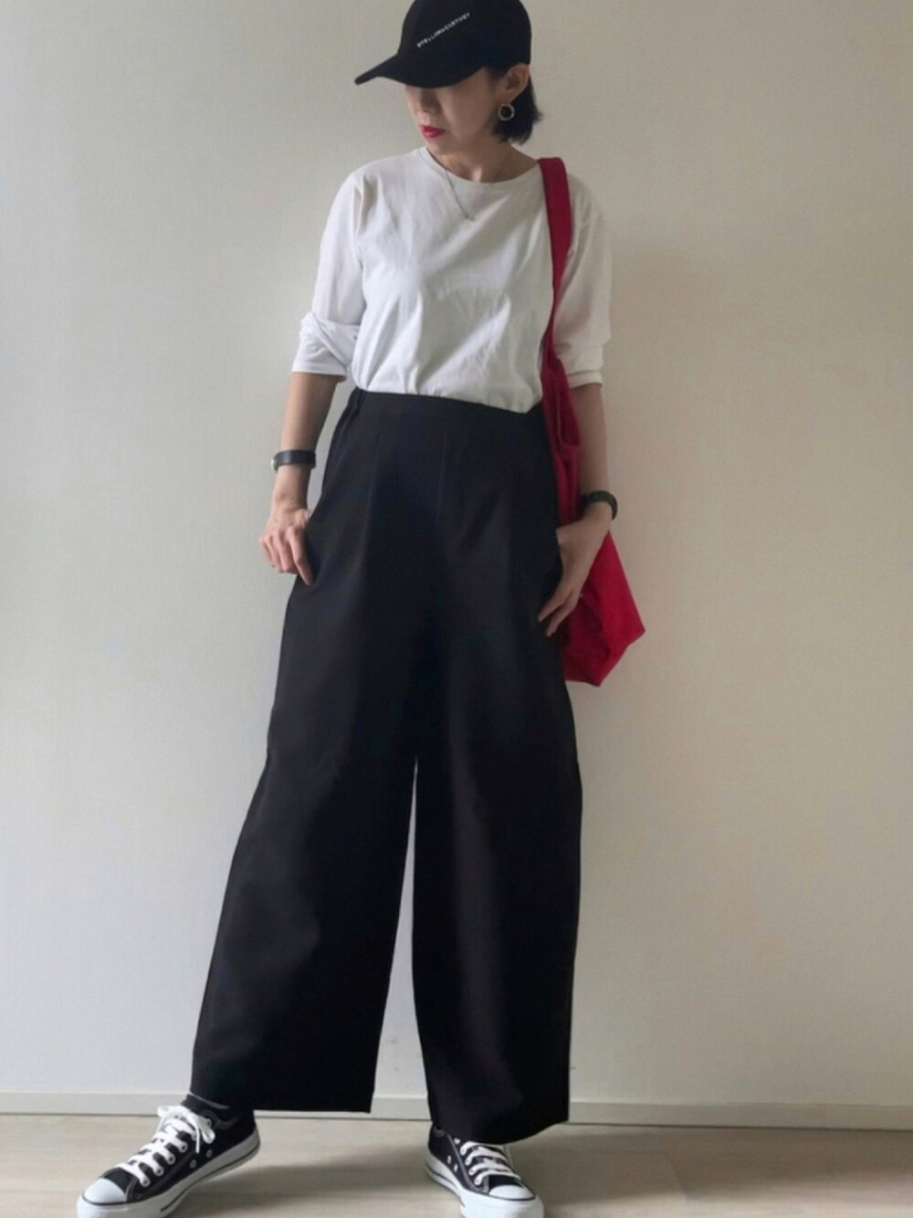 ブラック系のパンツ、ホワイト系のTシャツ/カットソー、ブラック系のスニーカーを着用したレディースの秋コーディネートの1枚目の写真
