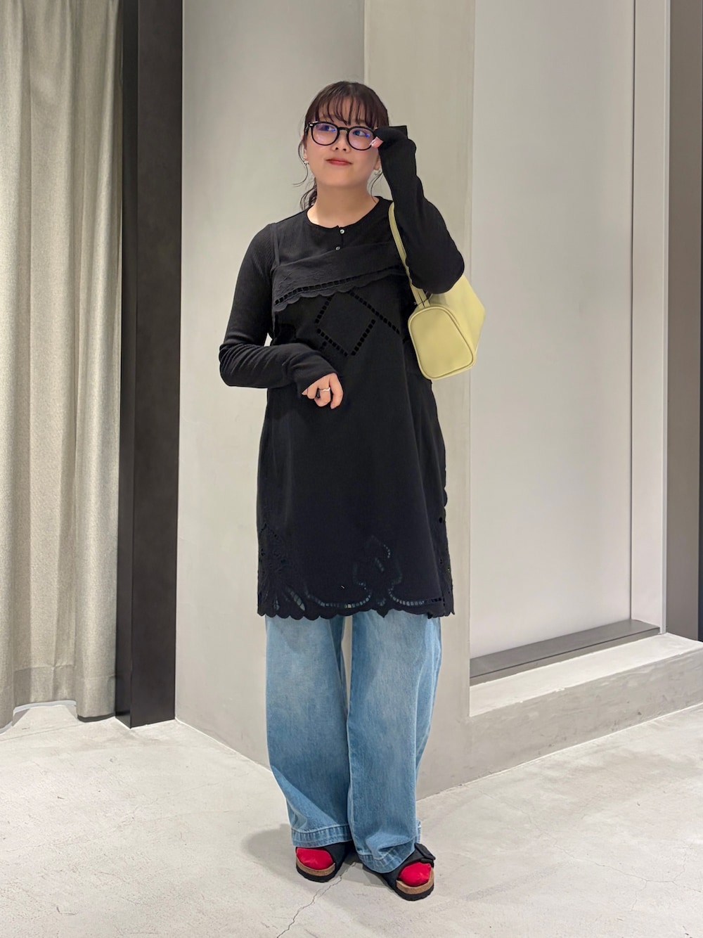 ブルー系のデニムパンツ、ブラック系のカーディガン/ボレロ、イエロー系のハンドバッグを着用したレディースの夏コーディネートの1枚目の写真