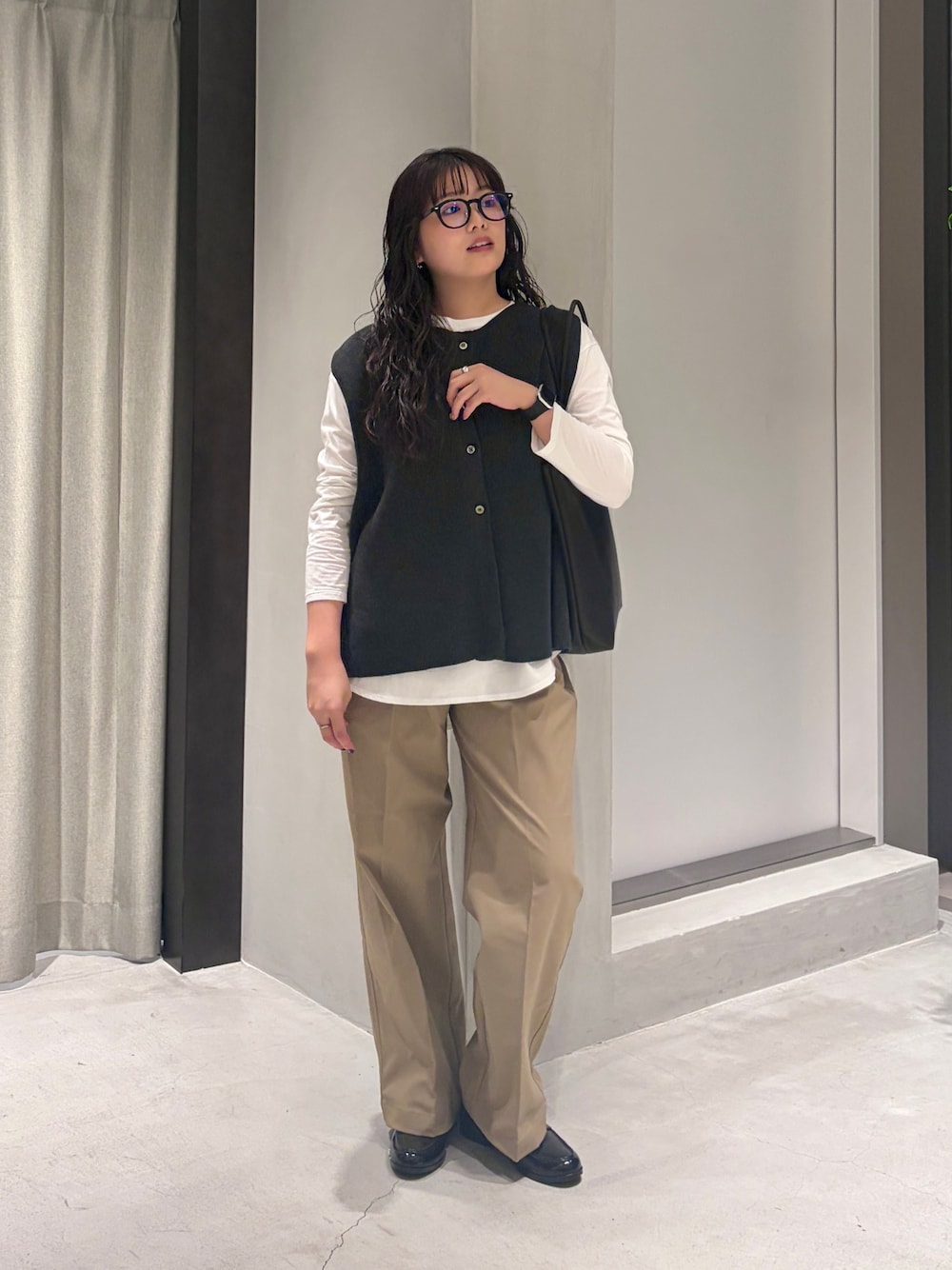 グレー系のベスト、ホワイト系のTシャツ/カットソー、ブラック系のトートバッグを着用したレディースの秋コーディネートの1枚目の写真