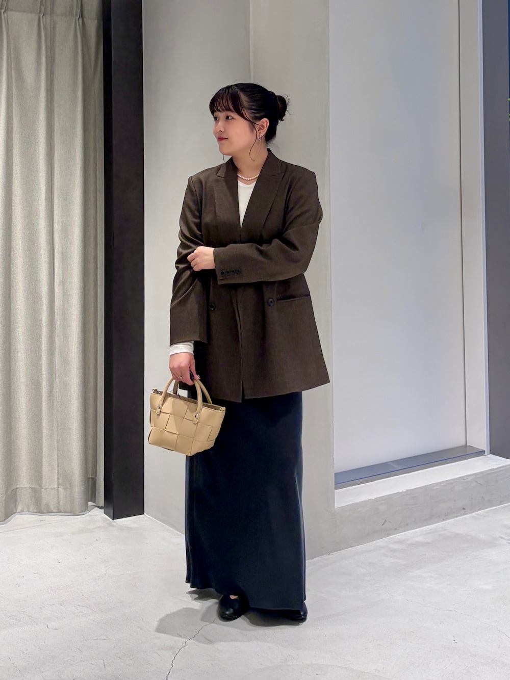 ブラウン系のその他アウター、ベージュ系のハンドバッグ、ブラック系のスカートを着用したレディースの秋コーディネートの1枚目の写真