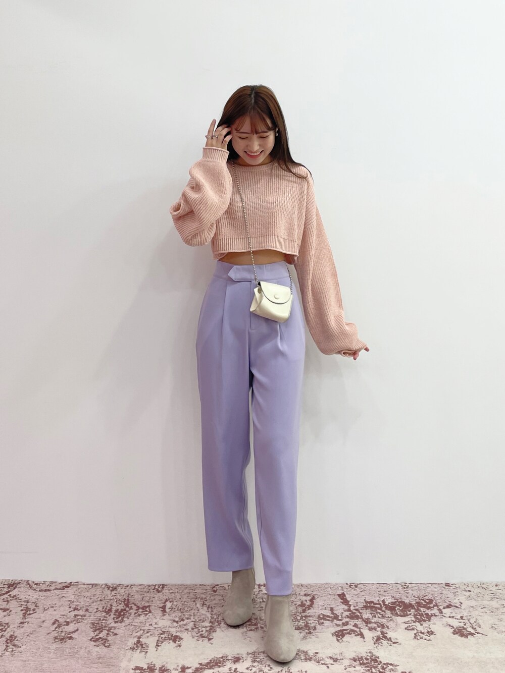 パープル系のスラックス、ベージュ系のブーツ、オレンジ系のニット/セーターを着用したレディースの夏コーディネートの1枚目の写真