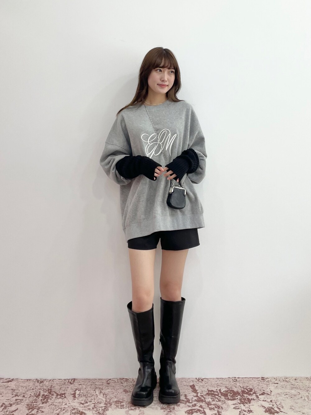 グレー系のスウェット、ブラック系のスカート、ブラック系のブーツを着用したレディースの秋コーディネートの1枚目の写真