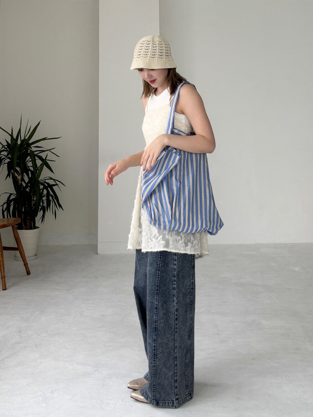 ブルー系のトートバッグ、ホワイト系のチュニック、ブルー系のデニムパンツを着用したレディースの夏コーディネートの1枚目の写真