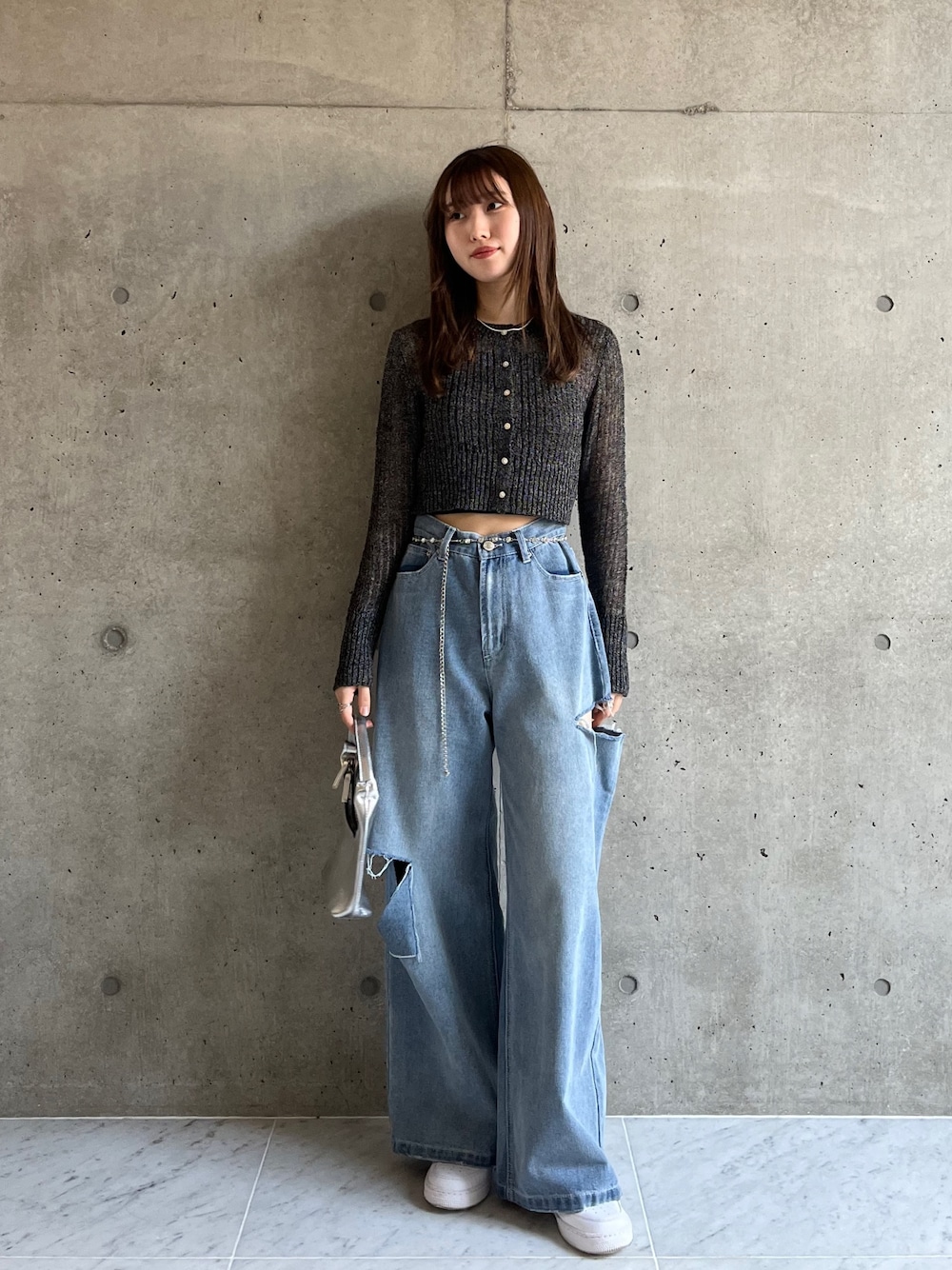 ブルー系のデニムパンツ、ブラック系のカーディガン/ボレロ、ホワイト系のスニーカーを着用したレディースの春コーディネートの1枚目の写真