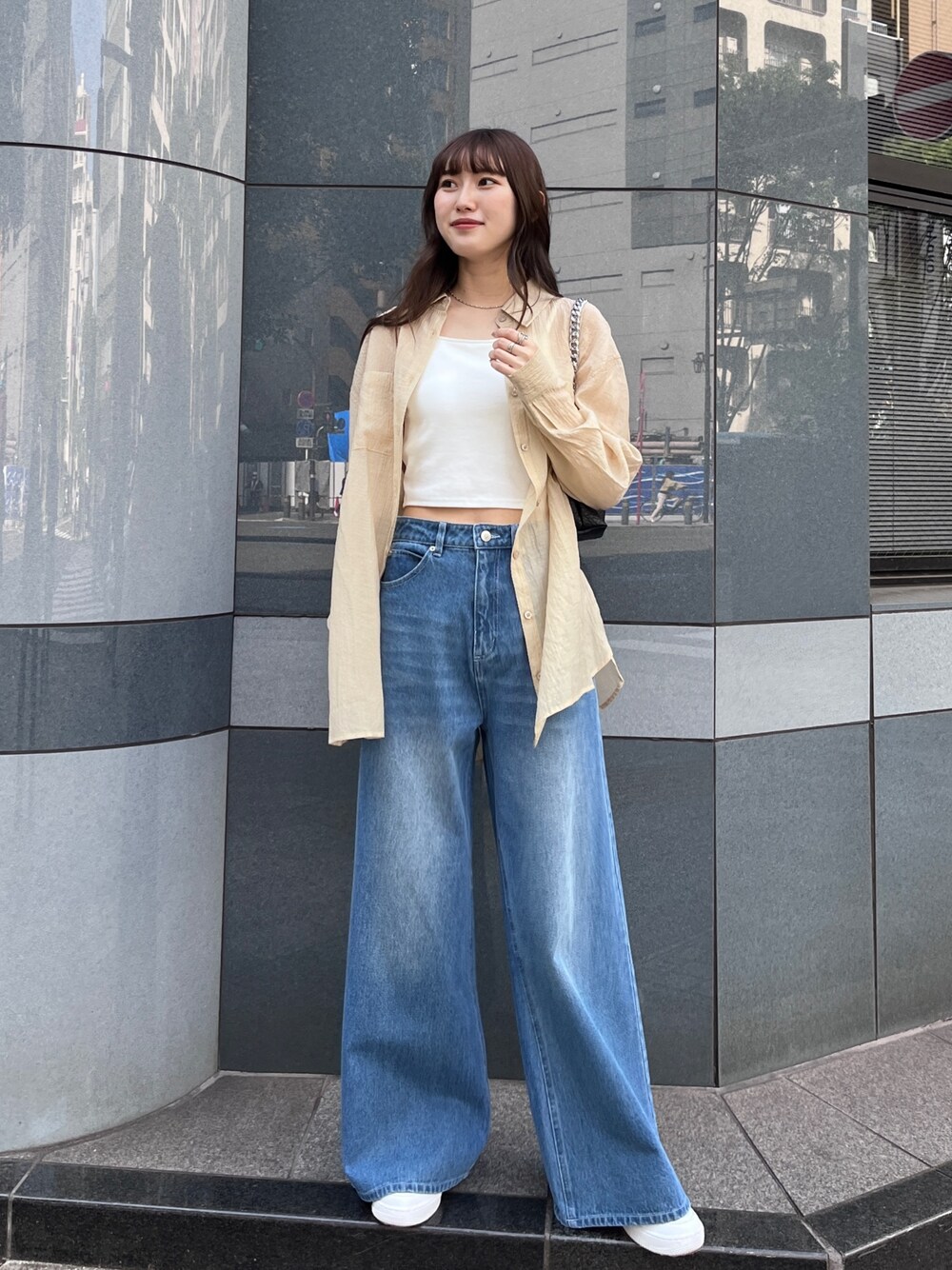 ブルー系のデニムパンツ、ベージュ系のシャツ/ブラウス、ホワイト系のキャミソールを着用したレディースの春コーディネートの1枚目の写真