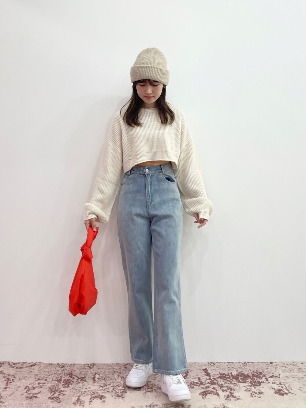 ホワイト系のニット/セーター、ブルー系のデニムパンツ、ホワイト系のスニーカーを着用したレディースの秋コーディネートの1枚目の写真