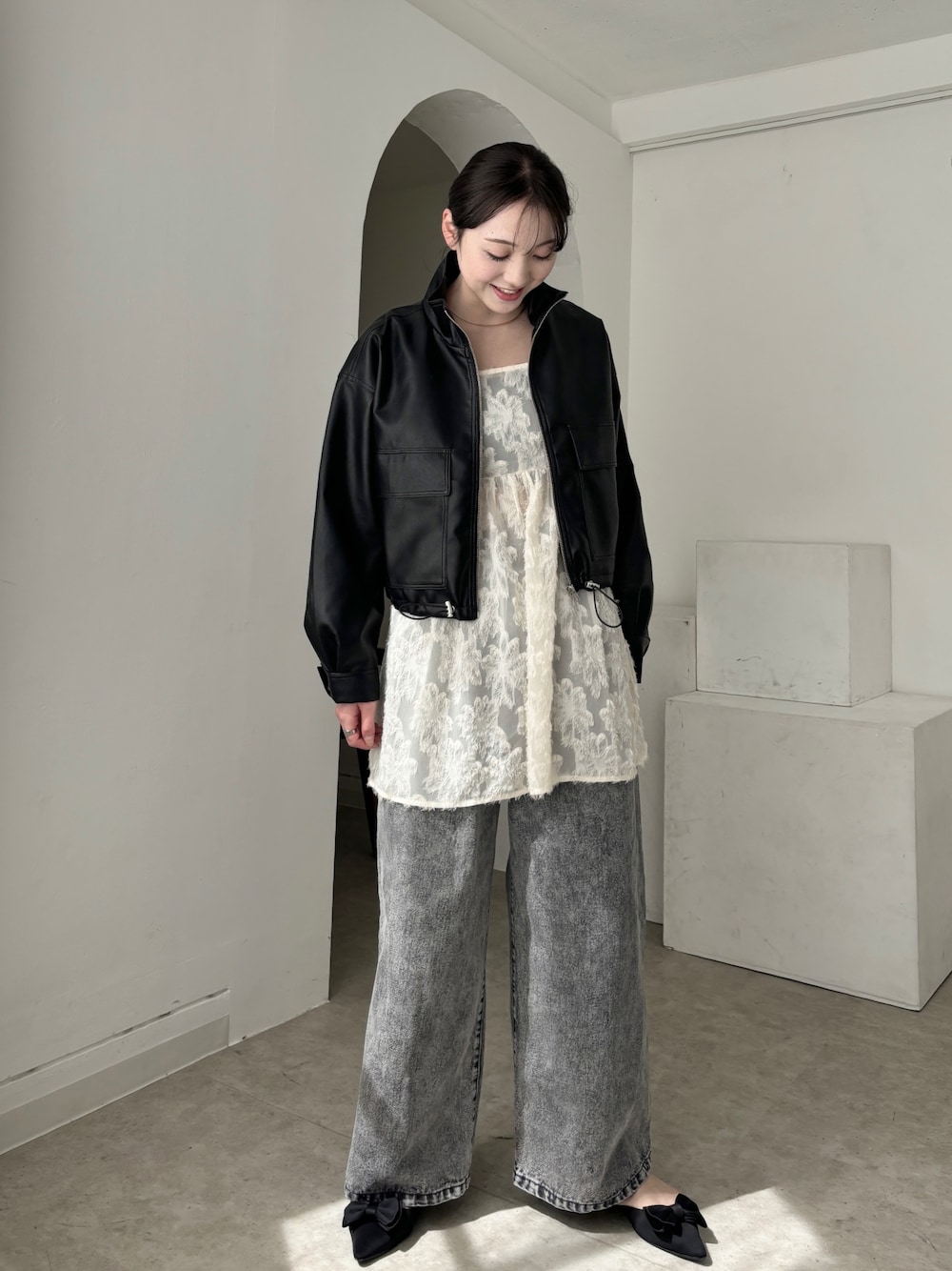 ホワイト系のチュニック、ブラック系のブルゾン、グレー系のデニムパンツを着用したレディースの春コーディネートの1枚目の写真
