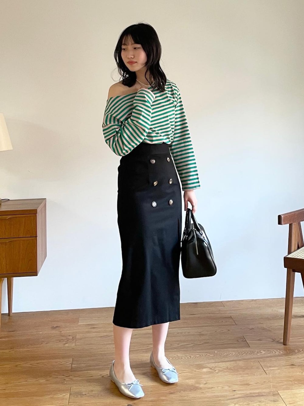 シルバー系のバレエシューズ、ブラック系のボストンバッグ、ブラック系のスカートを着用したレディースの冬コーディネートの1枚目の写真