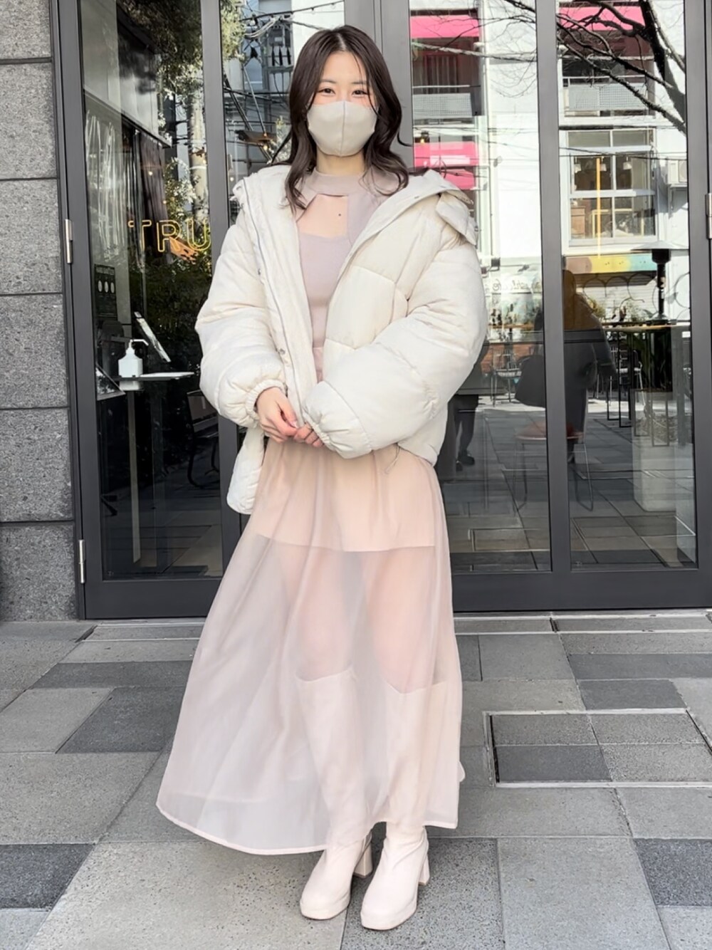 ベージュ系のダウンジャケット/コート、ピンク系のニット/セーター、ベージュ系のスカートを着用したレディースの冬コーディネートの1枚目の写真